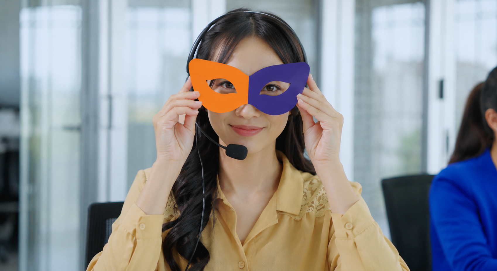 ヘッドセットのオペレーターが、オレンジと紺のマスカレード仮面を目もとに掲げている